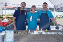 Photo of Kelsey Meyer and two oyster shuckers at Oyster Fest.