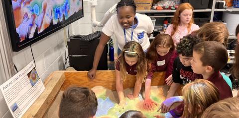 ODD volunteer with students in the ocean mapping sandbox. 