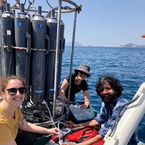 Three people on a boat in front of a rosette instrument. 