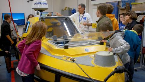 A group of people inspecting a small yellow boat.